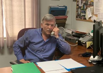 CUPE NB president Steve Drost sits at a desk speaking on the phone.
