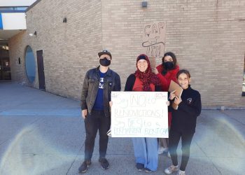 A group of four people outdoors, two holding placards calling for rent control.