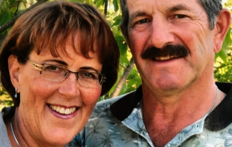 A woman and man stand close together, smiling at the camera