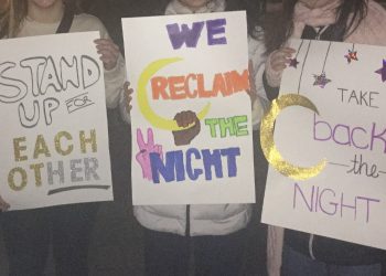 Protesters hold signs which say, "Take back the night."
