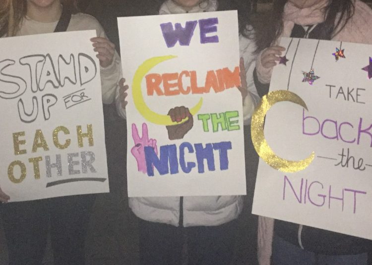 Protesters hold signs which say, "Take back the night."
