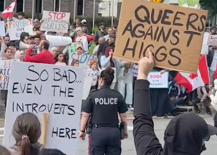 Protestors hold signs against anti- 2SLGBTQ+ Legislation.