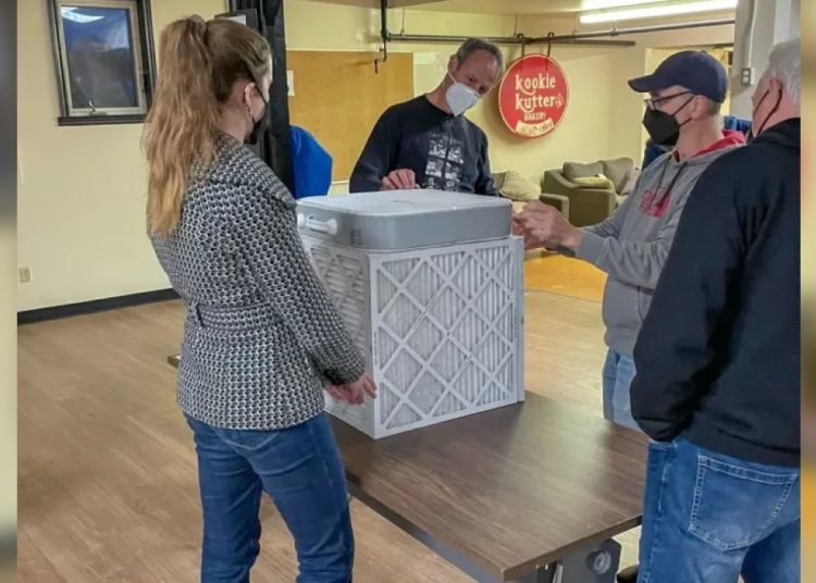 A group of people gathered around an air filter.