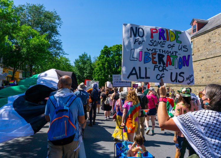 Protesters holding signs, one reading 'No Pride for Some of Us Without Liberation for All of Us'