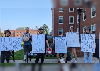 A group of protesters holding signs opposing police recruitment on the UNB Fredericton campus. Signs read messages such as "No cops on campus" and "RMCP Kills."