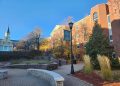 A sunlit, wide-angle view of the St. Thomas University campus in Fredericton during autumn.